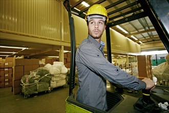 Caucasian worker driving machinery in warehouse