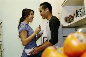 Smiling couple eating cereal in kitchen