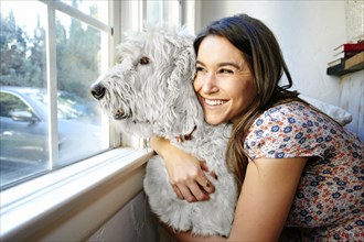 Caucasian woman hugging dog at window