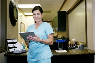 Caucasian nurse using digital tablet in office