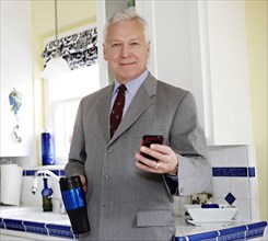 Businessman using cell phone in kitchen