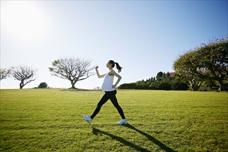 Pregnant mixed race woman exercising in field