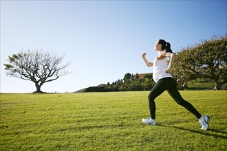 Pregnant mixed race woman jogging in field