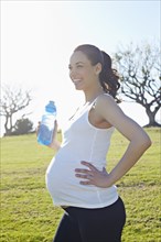 Pregnant mixed race woman standing in field