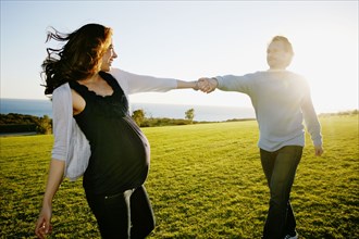 Pregnant couple playing in field