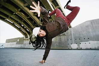 Hispanic woman break dancing under overpass
