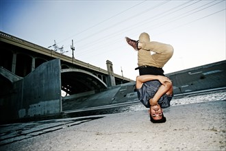 Mixed race man break dancing under overpass