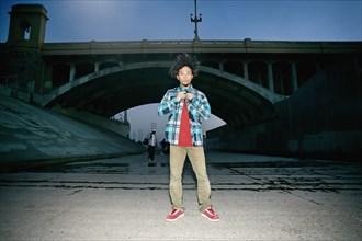 Asian man standing under overpass
