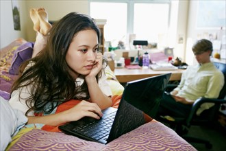 Mixed race college student using laptop in dorm