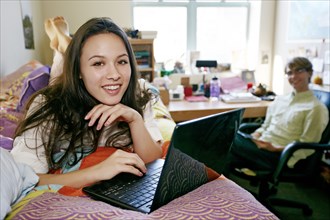 Mixed race college student using laptop in dorm