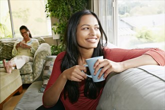 Indian woman having cup of coffee on sofa