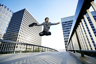 Asian businessman leaping on urban walkway