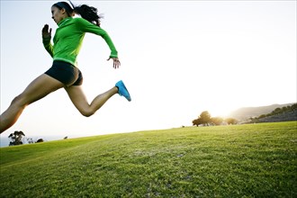Hispanic woman running in rural landscape