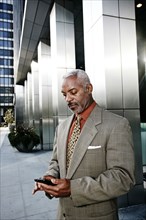 Black businessman using cell phone on city street