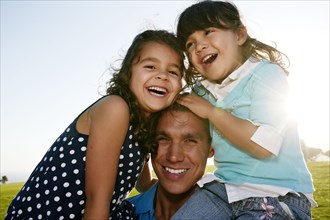 Father and daughters smiling in field