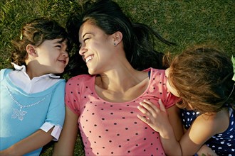 Mother and daughters smiling in grass