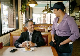 Hispanic waitress talking to businessman in restaurant
