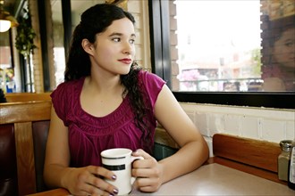 Mixed race woman having coffee in restaurant