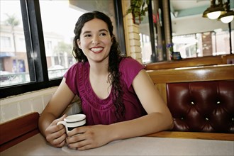 Mixed race woman having coffee in restaurant