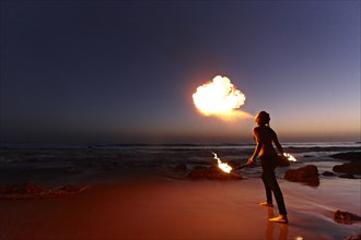 Woman breathing fire on beach