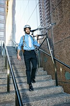 Caucasian businessman carrying bicycle down urban stairs