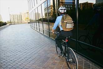 Caucasian businessman riding bicycle outside building