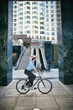 Caucasian businessman riding bicycle outside highrise