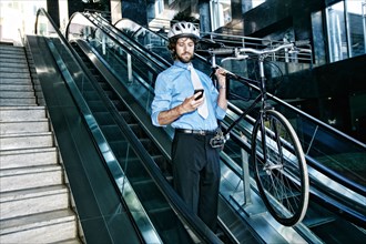 Caucasian businessman carrying bicycle on escalator