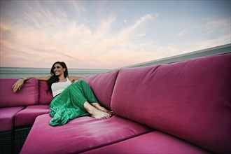 Middle Eastern woman relaxing on sofa outdoors