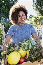 Mixed race woman harvesting vegetables in garden