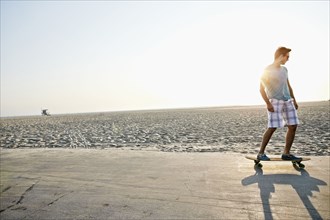 Caucasian man skating on beach