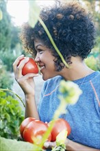 Mixed race woman smelling tomatoes in garden