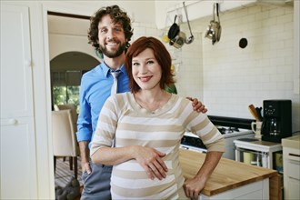 Pregnant Caucasian couple smiling in kitchen