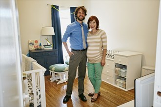 Pregnant Caucasian couple smiling in nursery