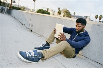 Black man using digital tablet on urban rooftop