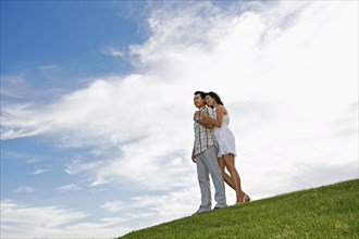 Couple hugging on grassy hillside
