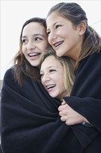 Teenage girls wrapped in blanket together