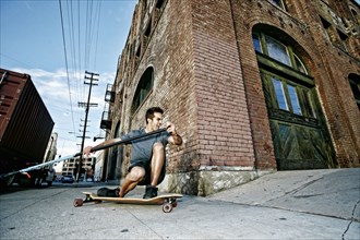 Caucasian man riding skateboard with land paddle