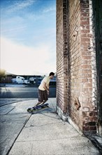 Caucasian man riding skateboard on city street