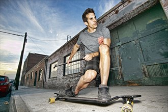 Caucasian man riding skateboard with land paddle