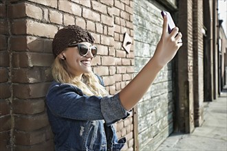 Woman taking picture of herself on city street