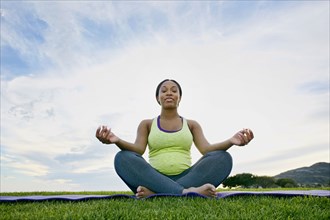 Pregnant woman meditating in park