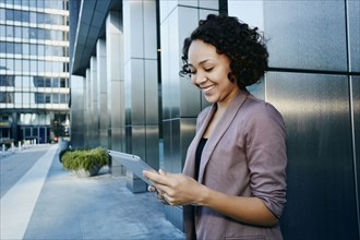 Mixed race businesswoman using tablet computer in city