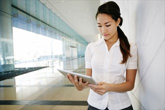 Mixed race businesswoman using tablet computer in lobby
