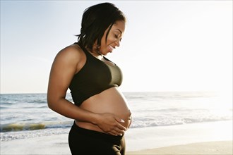 Pregnant woman holding her belly on beach