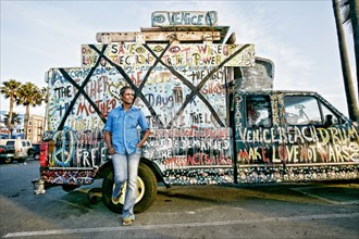 Older Black woman standing by decorated truck