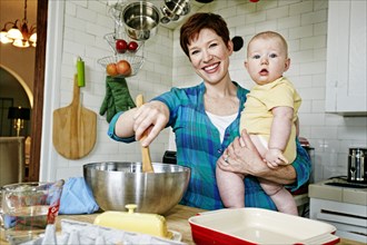 Caucasian mother cooking with baby in kitchen