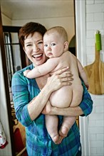 Caucasian mother holding nude baby in bathroom