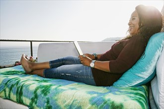 Mixed race woman using digital tablet at waterfront