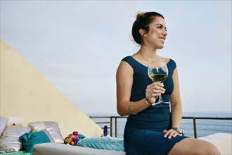Mixed race woman drinking wine at waterfront